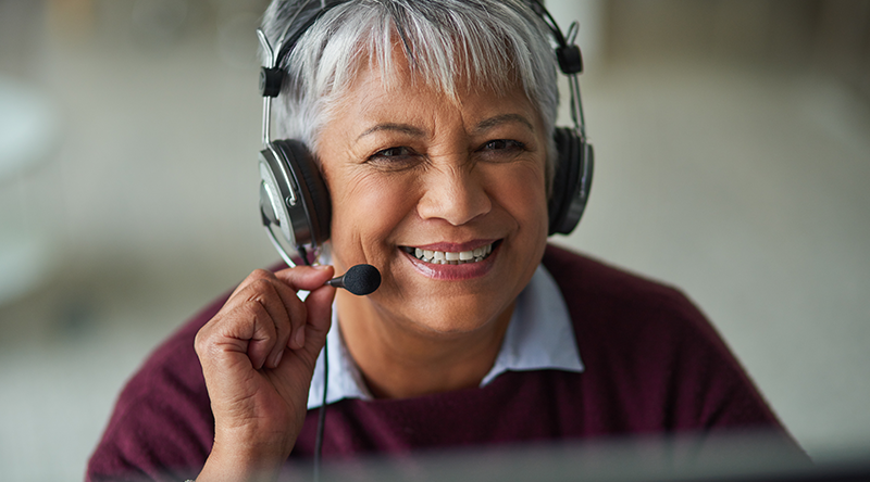smiling employee adjusting headset while assisting clients on the phone