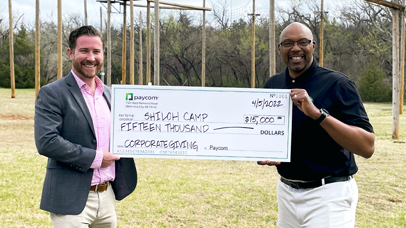 Paycom employees presenting corporate giving check to recipient.